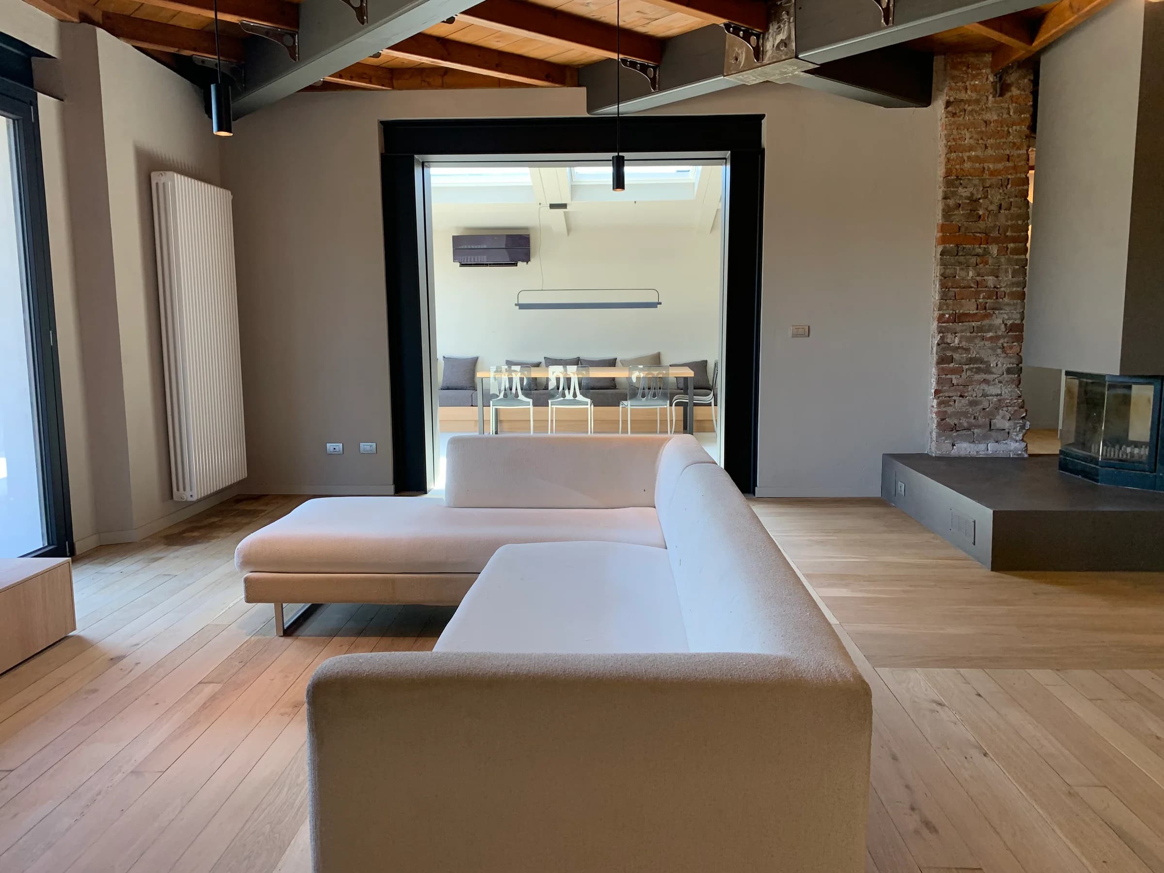 Living ristrutturato con travi a vista e dettagli in laterizio