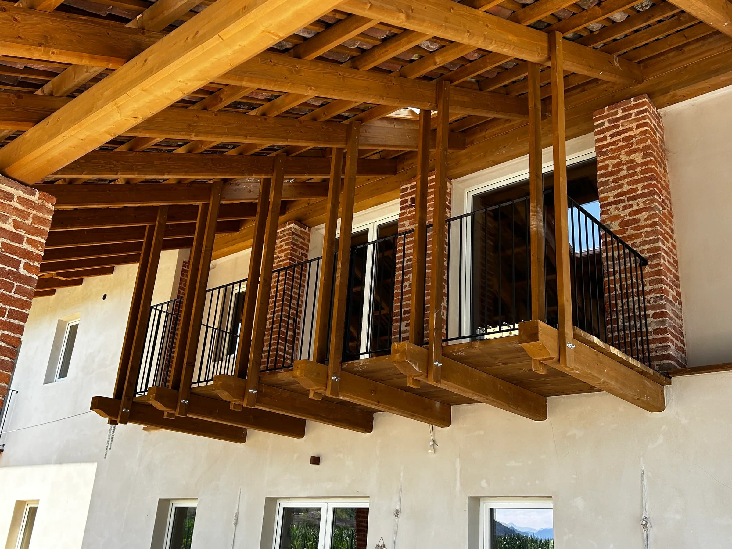 Facciata con balcone in legno e pilastri in mattoni — Busca